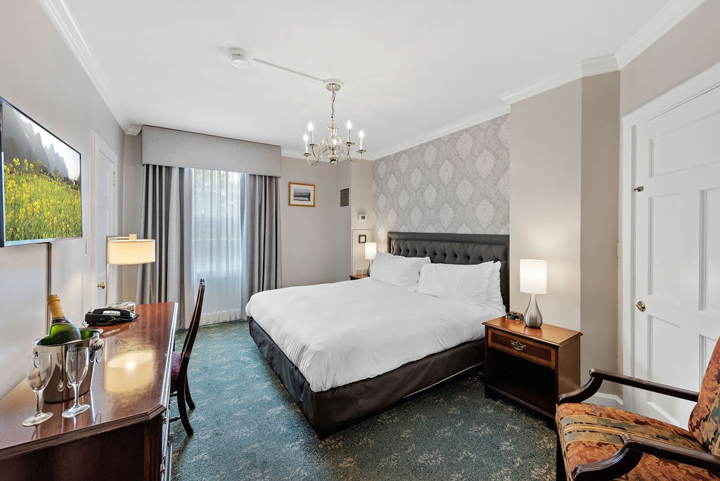 Image of Standarm Guestroom at the Hawthorne Hotel with king-sized bed, hanging chandelier, writing desk, and accent chair. A member of Historic Hotels of America since 1991, located in Salem, Massachusetts